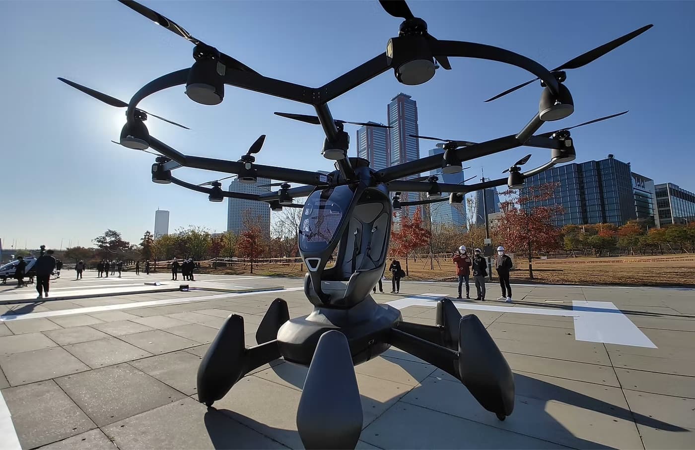 A large multirotor aircraft standing in a city plaza, seen from below
