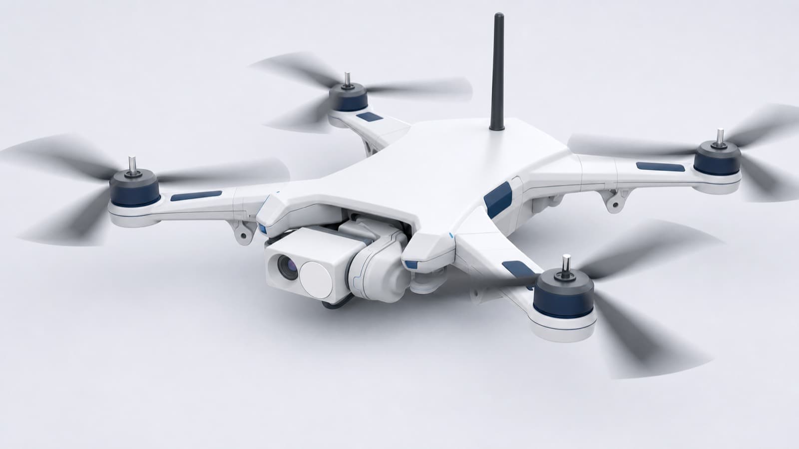 A white quadcopter with a gimbal-mounted camera under its nose, rotors turning, photographed against a plain background
