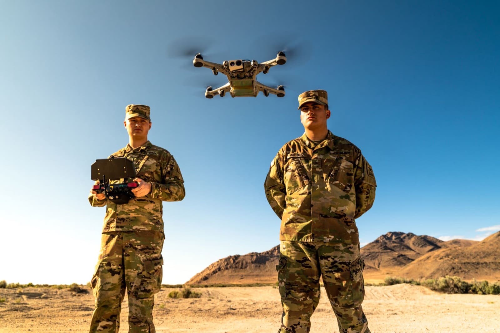 Two operators in the field, one flying a small drone from a handheld controller
